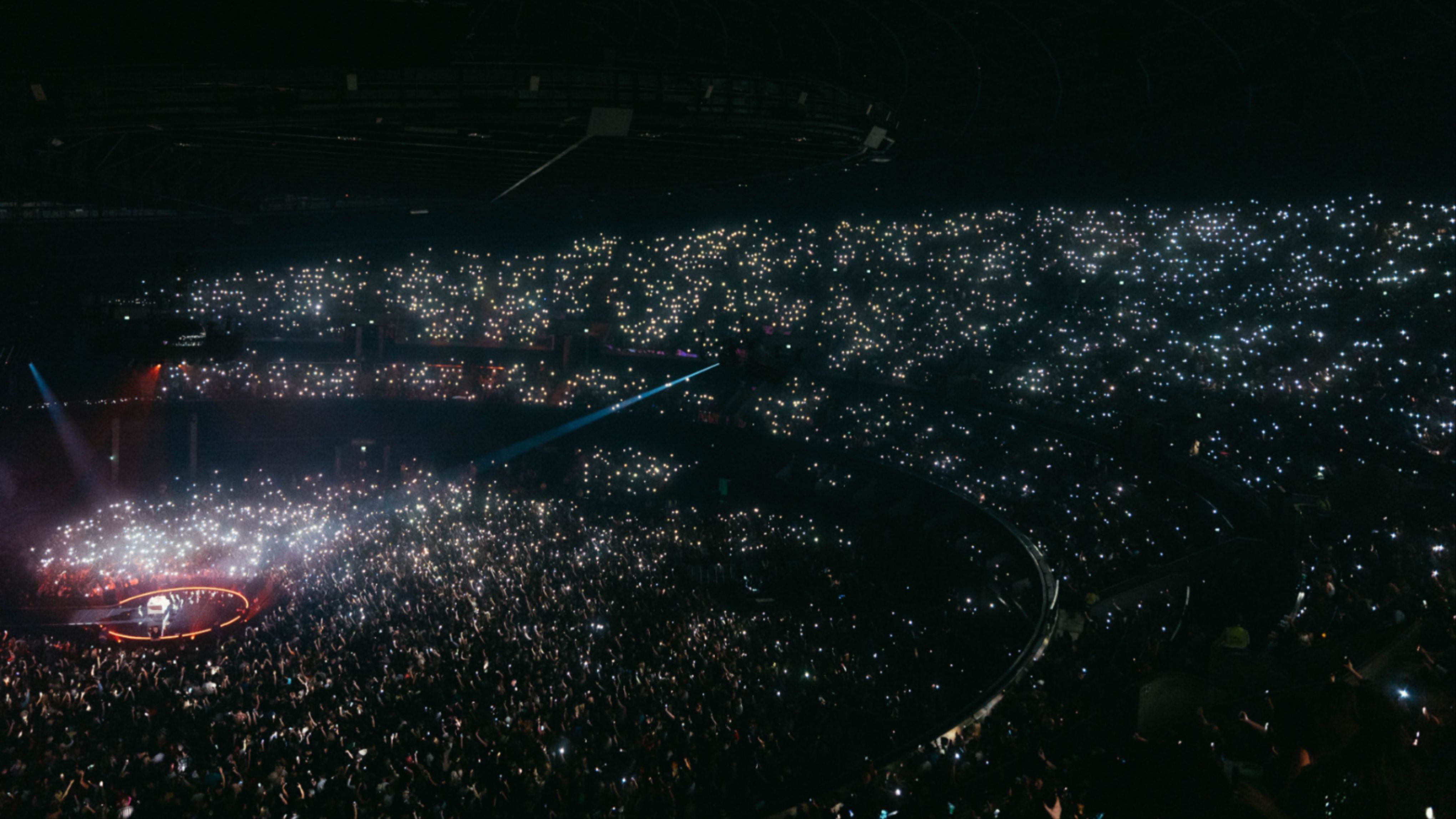 A live audience at OVO Hydro with the audience holding their phones in the air with the torch on.