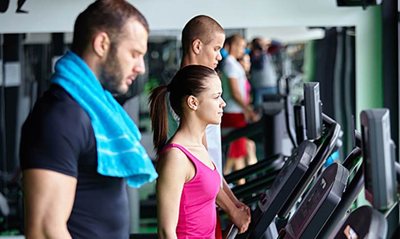 Two men and a woman on gym equipment.