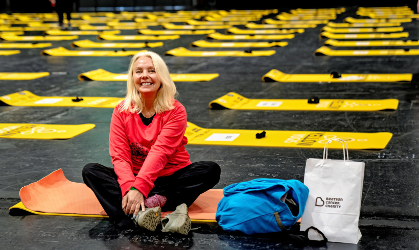woman sitting on yoga mat surrounded by yellow yogis yoga matts